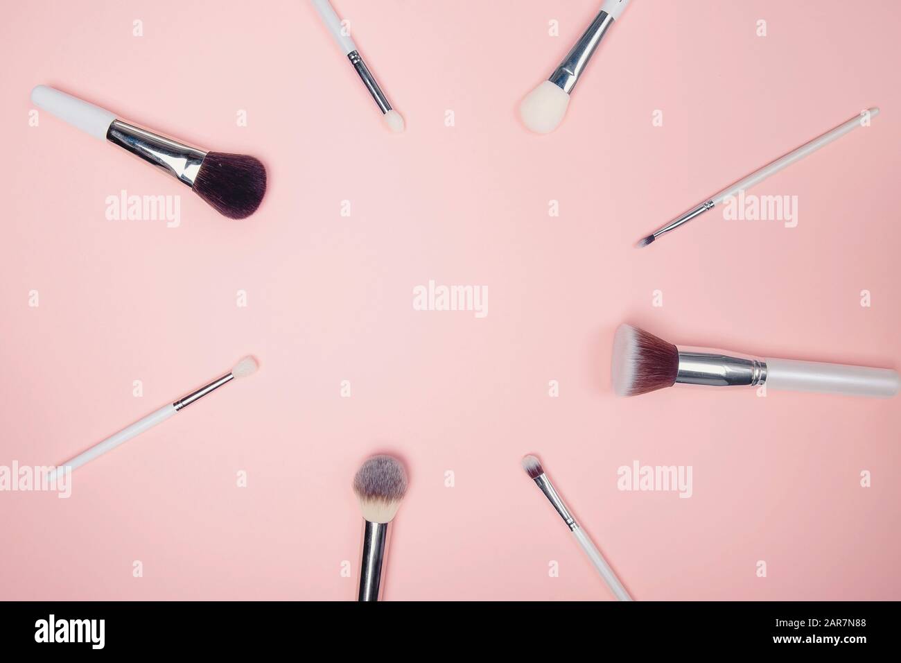 Imposta le spazzole per il trucco del kit su sfondo rosa, vista dall'alto a disposizione piatta Foto Stock