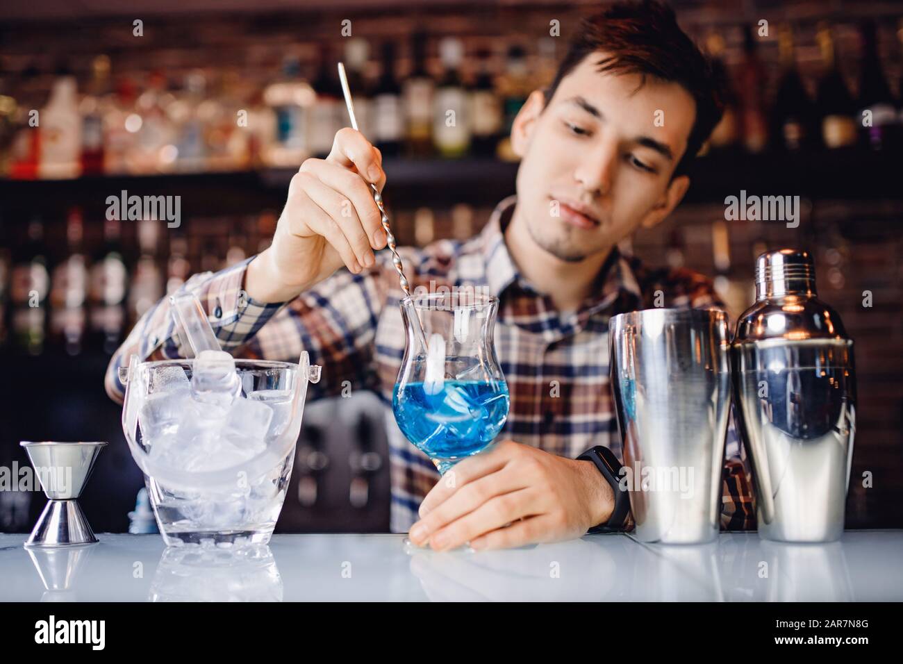 Il barman mescola il cocktail con il colorato bancone del bar con cocktail alcolici Foto Stock