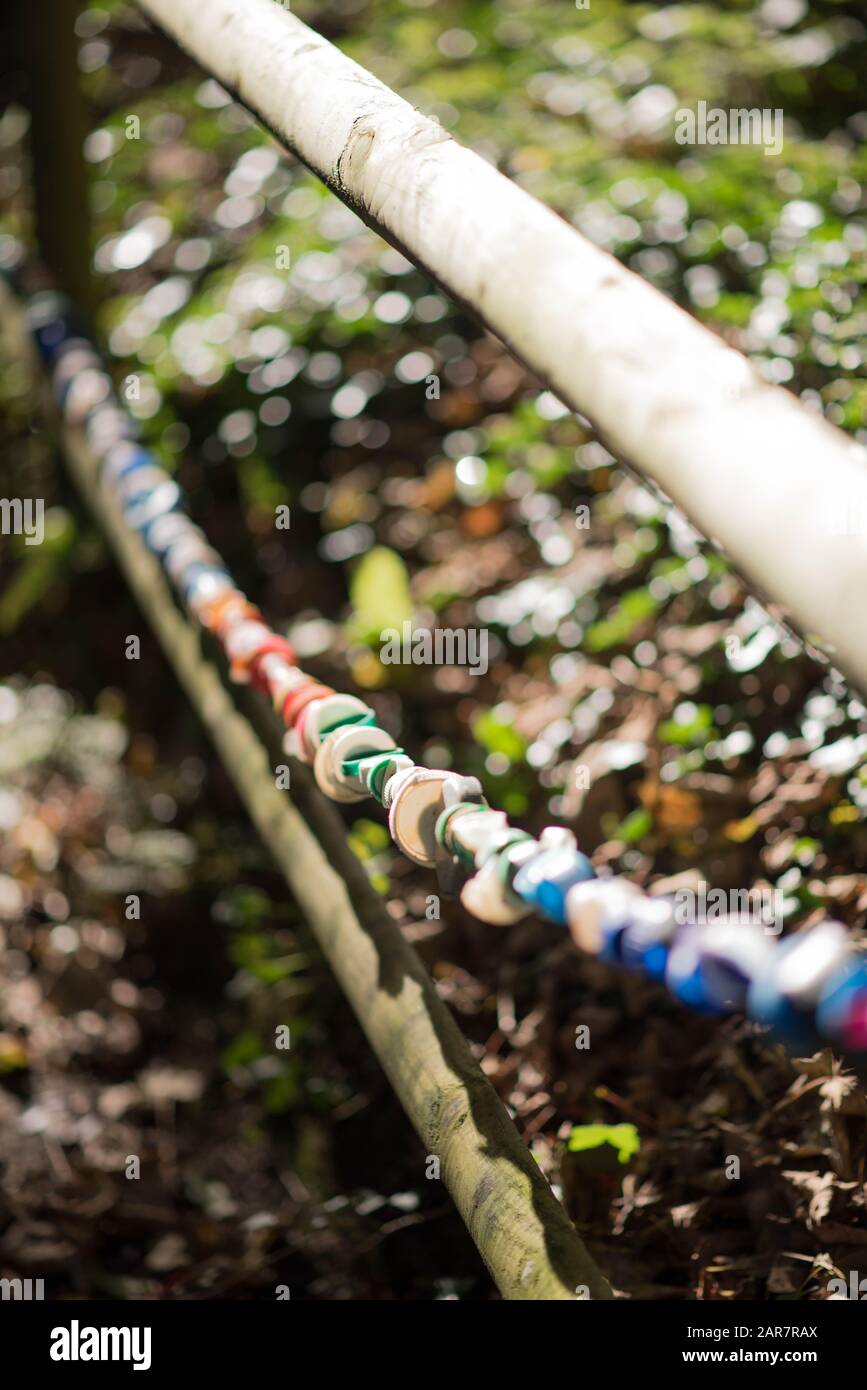 Mostra di tappi in plastica per bottiglie stesi lungo la scherma come un'esposizione di opere d'arte ambientale che promuove il riciclaggio Foto Stock