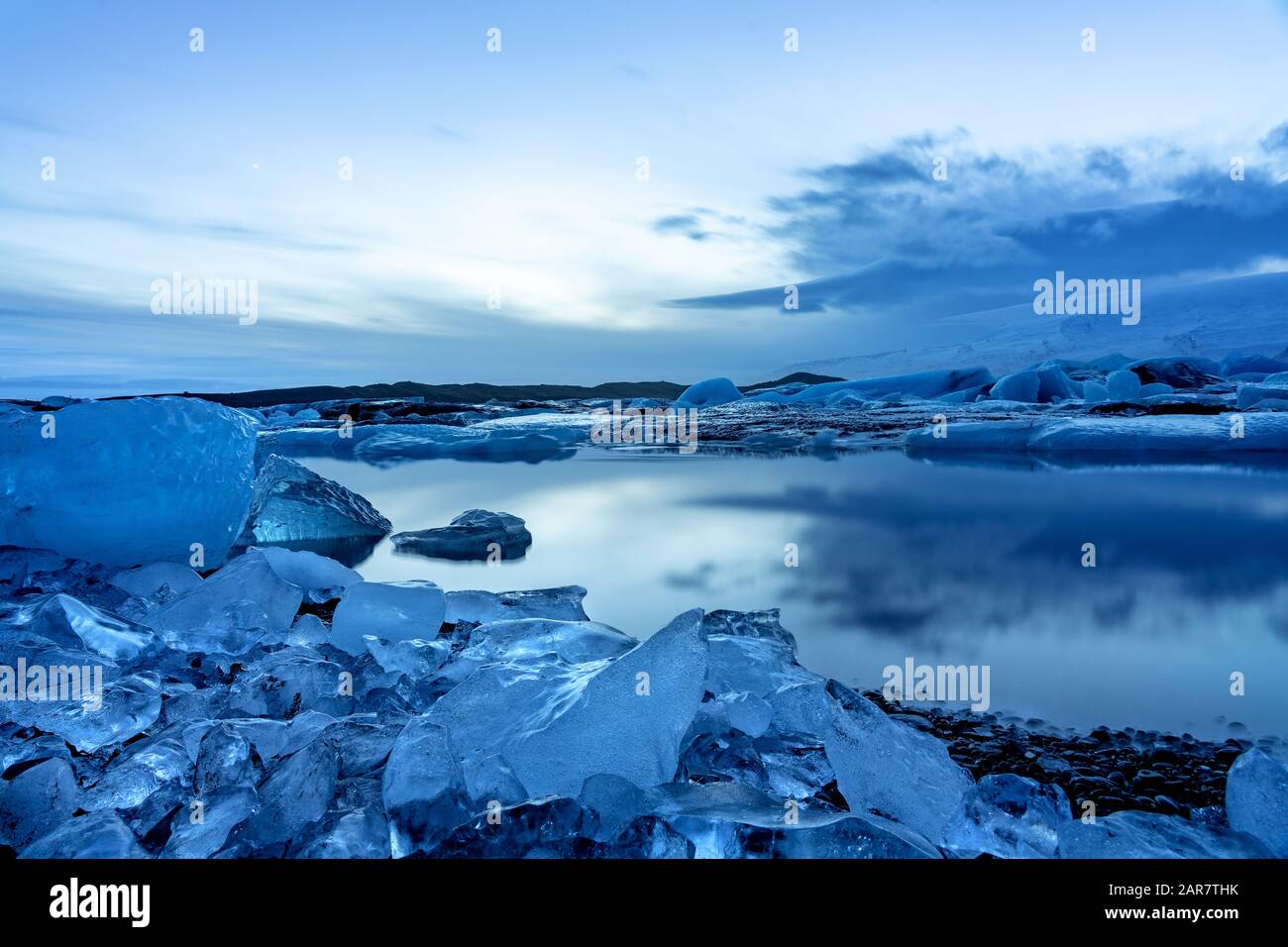 ghiacciaio dell'islanda jokulsarlon negli iceberg serali che galleggiano sull'acqua fredda e tranquilla dopo il tramonto con cielo drammatico. Foto Stock