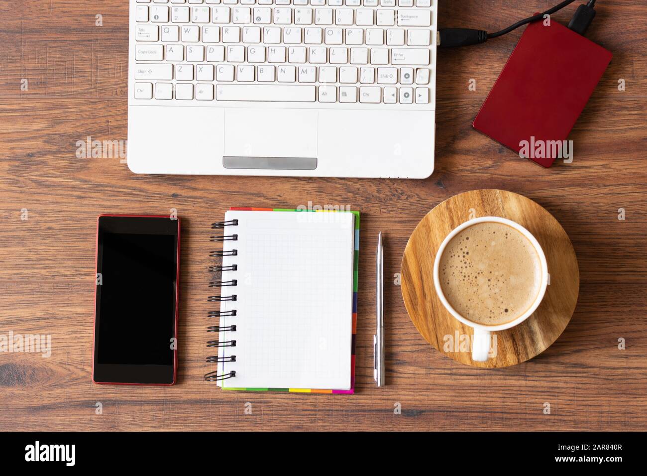 Spazio di lavoro con computer portatile, agenda e una tazza di caffè su sfondo di legno. Ambiente di lavoro elegante per l'ufficio. Spazio di copia. Disposizione piatta. Foto Stock