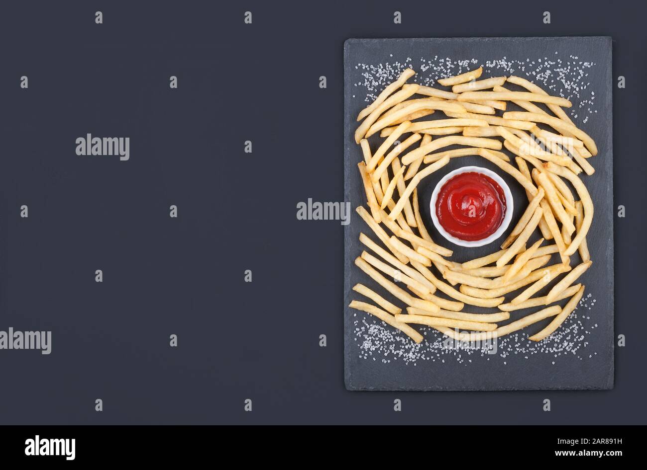 Patatine fritte dorate con ketchup sulla tavola grigia su sfondo grigio. Disposizione piatta con spazio per la copia. Foto Stock