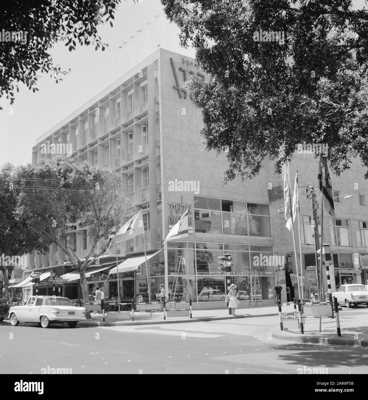Israele 1964-1965 Tel Aviv. Condominio con piano terra compreso il bookshop Alcheh. Sui marciapiedi flagelli con bandiere fluttering Data: 1964 Località: Israele, Tel Aviv Parole Chiave: Libreria, condomini, sculture di strada, bandiere Foto Stock