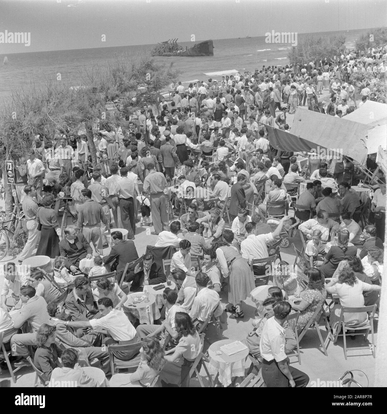 Israele 1948-1949: Tel Aviv Tel Aviv. Terrazza sovraffollata sul lungomare di sabato mattina con vista sul relitto dell'Altalena Data: 1948 luogo: Israele, Mar Mediterraneo, Tel Aviv Parole Chiave: Boulevards, caffè, onde, pubblico, incidenti navali, spiagge, terrazze, relitti Foto Stock