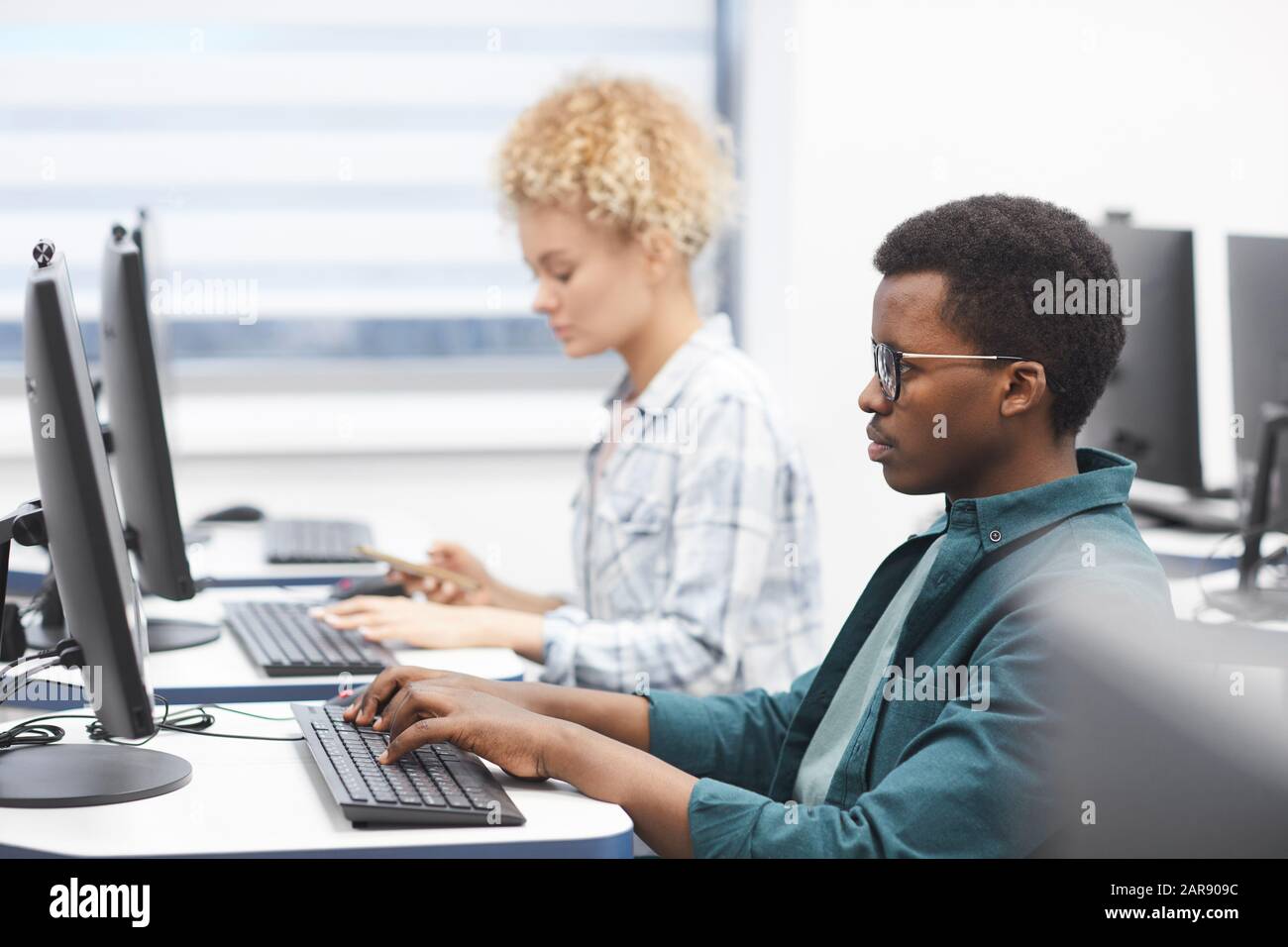 Ritratto di vista laterale di uomo afro-americano usando il calcolatore nella classe della biblioteca dell'università, spazio della copia Foto Stock