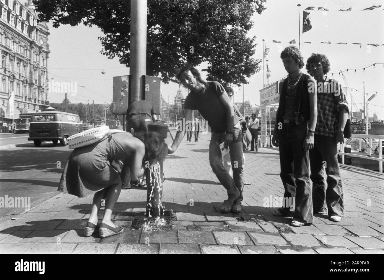 Giornata estiva più calda ad Amsterdam Passers-by drink acqua da una pompa su Damrak Data: 4 agosto 1975 luogo: Amsterdam, Noord-Holland Parole Chiave: Bevitori, acqua potabile, immagini di strada, calore, estate Foto Stock