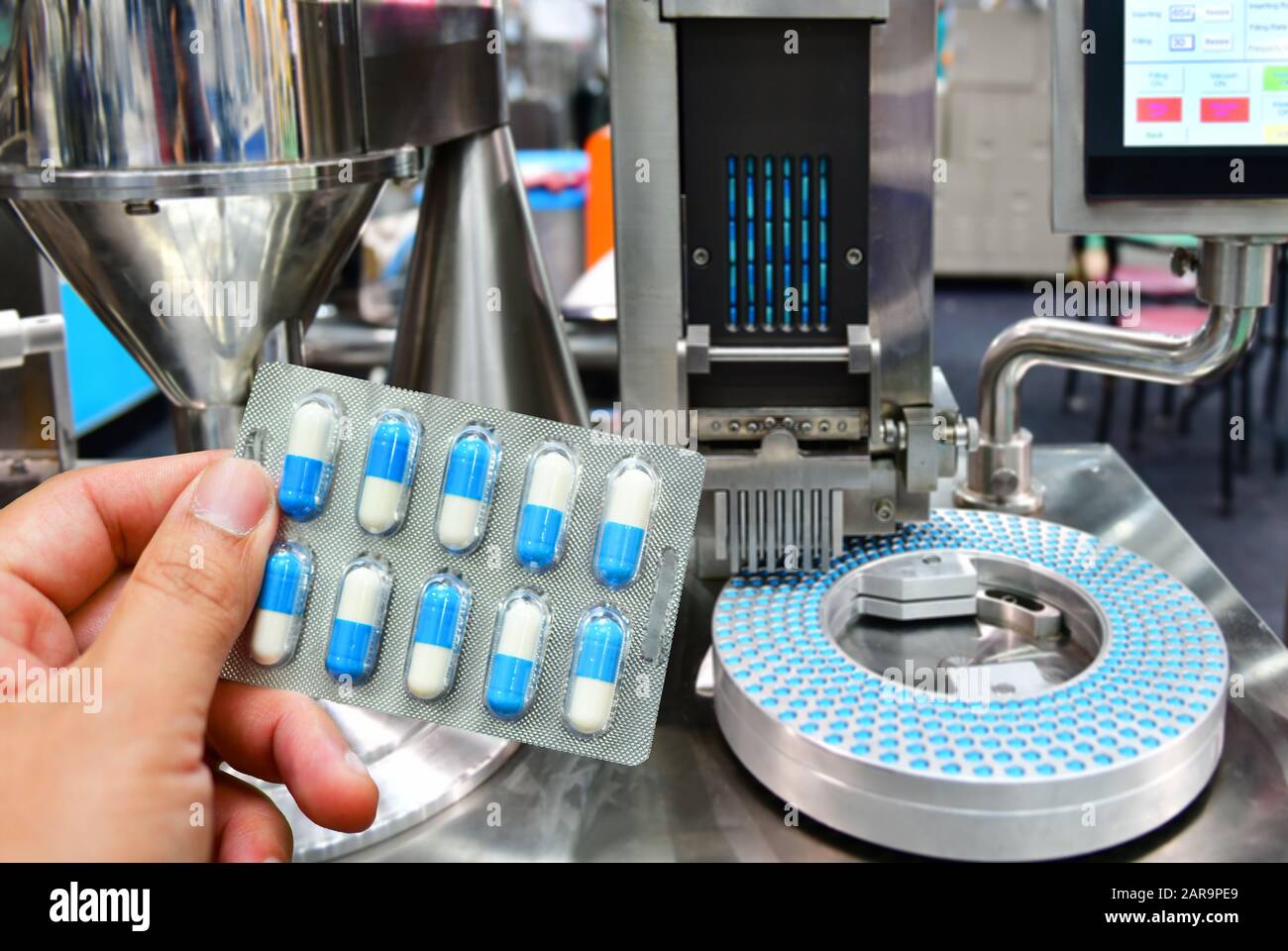 Confezione di capsule blu per la conservazione delle mani presso la linea di produzione di pillole mediche, concetto farmaceutico industriale. Foto Stock