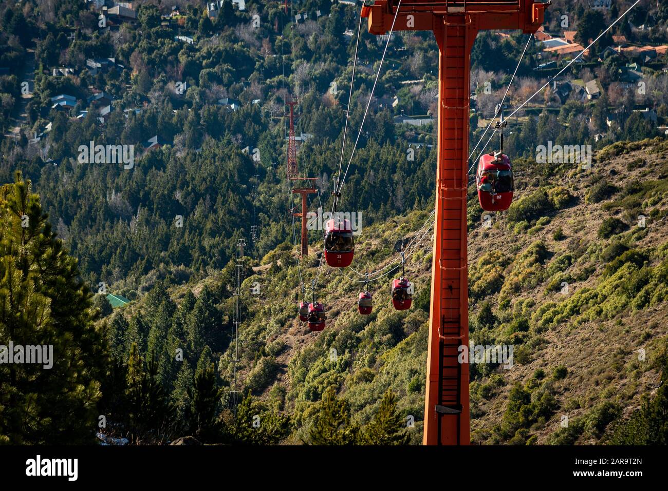 Vista prospettica delle funivie rosse che trasportano i passeggeri sulla cima delle montagne viste sullo sfondo. Foto Stock
