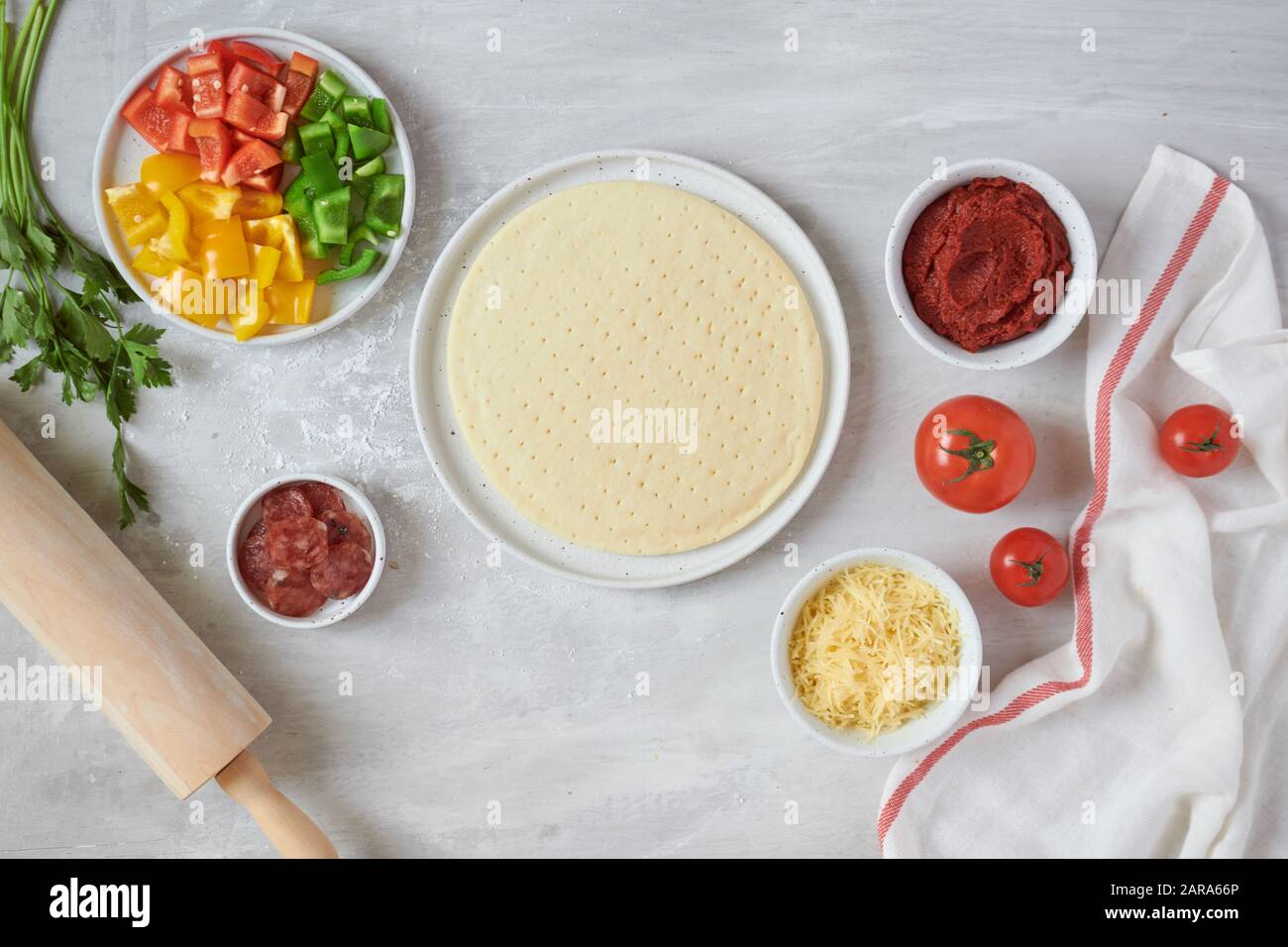 Pasta fresca la base della pizza e gli ingredienti su un tavolo bianco. Vista dall'alto. Foto Stock