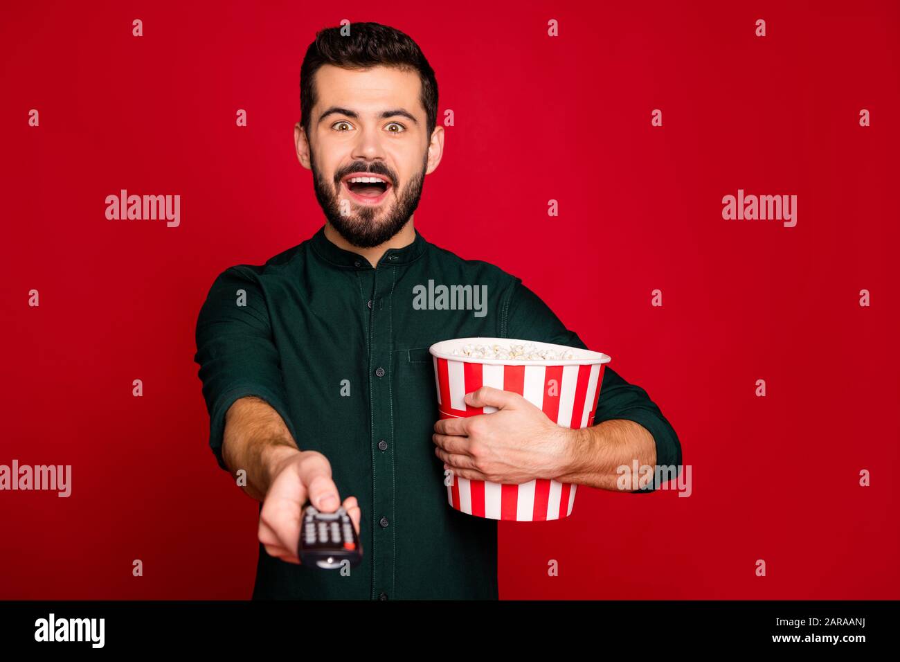 WOW il mio film preferito. Ragazzo pazzo eccitato avendo riposo guardare tv scream tenere grande rosso a righe pop corn box interruttore telecomando indossare abiti moderni Foto Stock