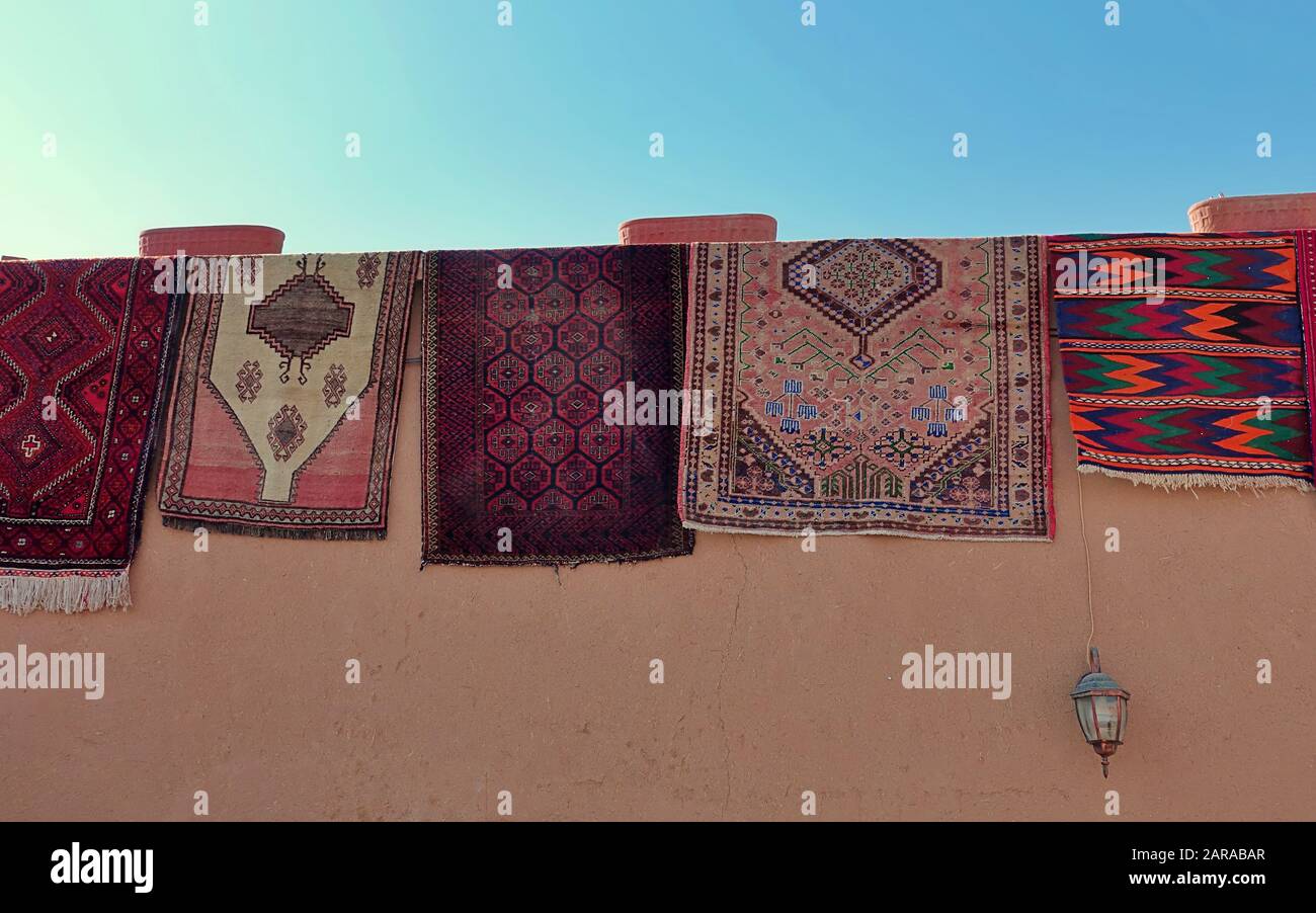 Colorati tappeti persiani fatti a mano pende sulle pareti di una casa di fango Foto Stock