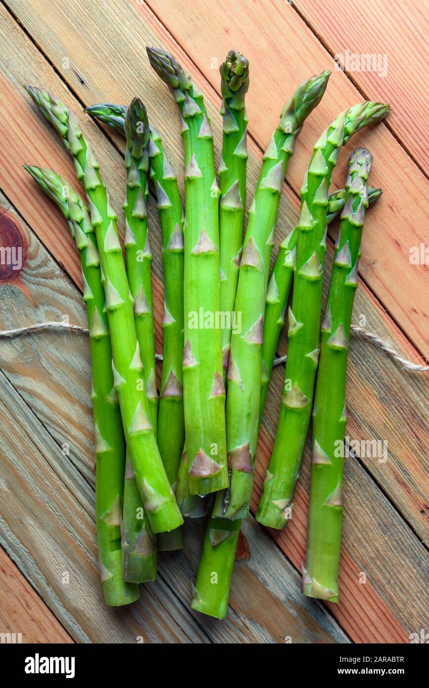 Gli asparagi verdi germogliano sulla tavola di legno closeup. Vista superiore piatta. laici Fotografia di cibo Foto Stock