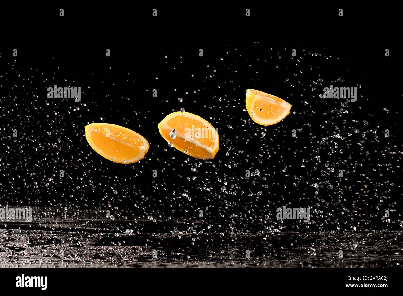 Fresche limone giallo metà in acqua splash su sfondo nero con un sacco di bolle di aria. Foto Stock