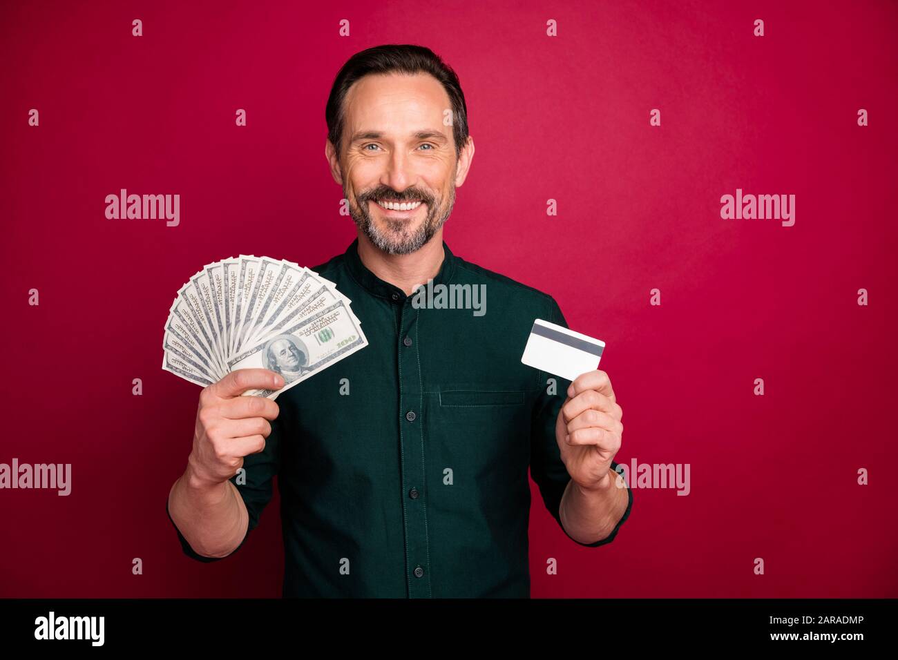 Primo piano ritratto del suo lui bello attraente allegro bearded uomo di successo che tiene in mano freelance 100 carta di plastica isolato su brillante brillante brillante brillante brillantezza Foto Stock