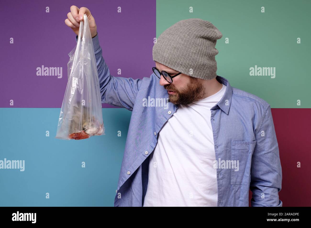 Uomo con antipatia guardando il pesce puzzolente in una borsa trasparente. Foto Stock