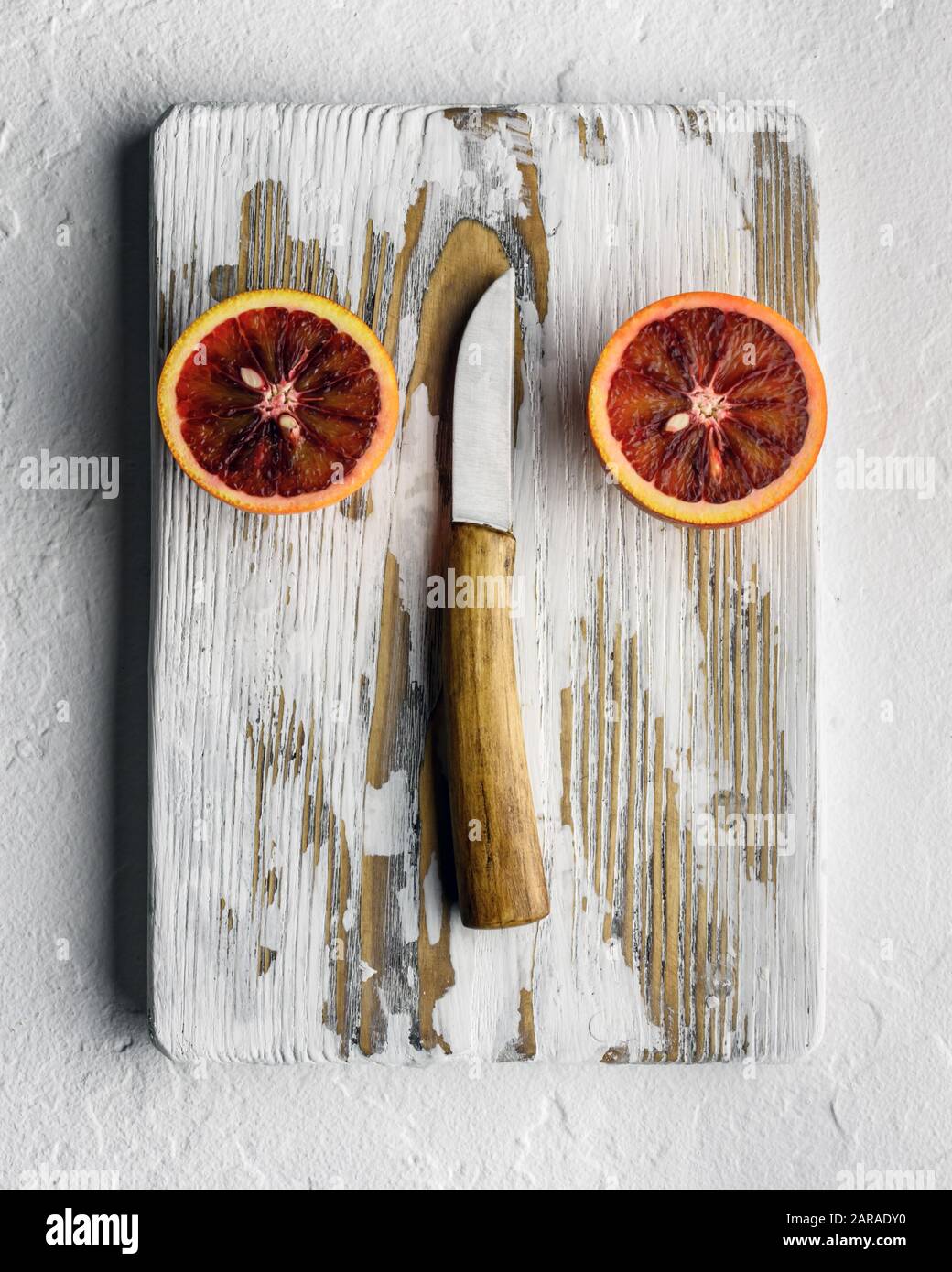 Semi pezzi arancioni con coltello su pannello di legno bianco primo piano. Dieta sana concetto di vitamina. Fotografia di cibo Foto Stock