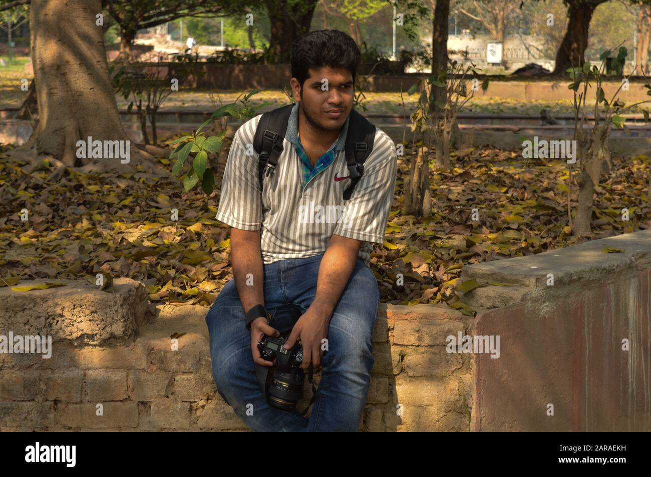 Un ragazzo indiano, ragazzo con fotocamera nikon D750 fare foto e posare dentro di giardino e lago al mattino. Foto Stock