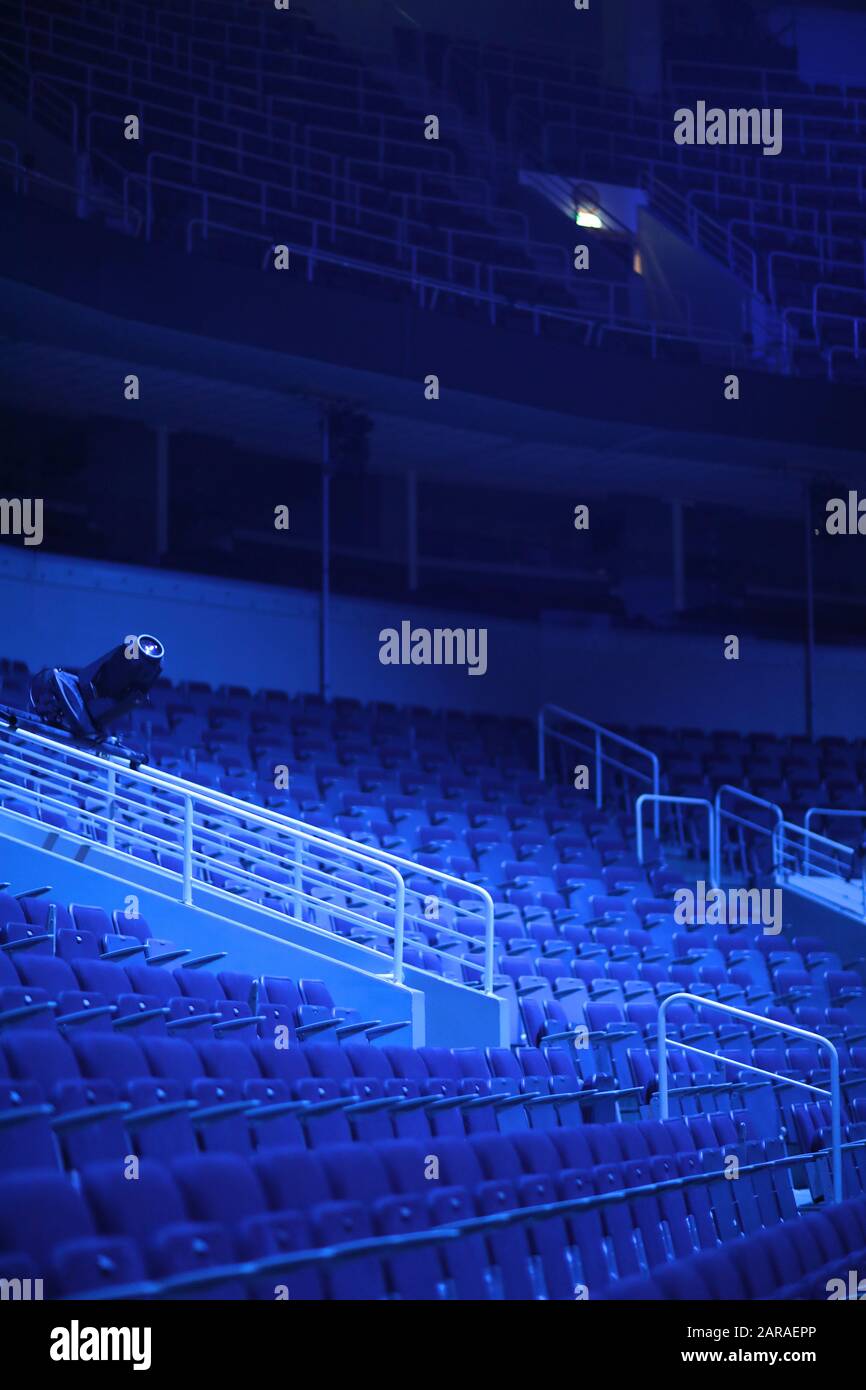 File vuote di sedili con braccioli in un auditorium multiuso alla luce dei fari blu Foto Stock File vuote di sedili con braccioli in un auditorium multiuso alla luce dei fari blu Foto Stock