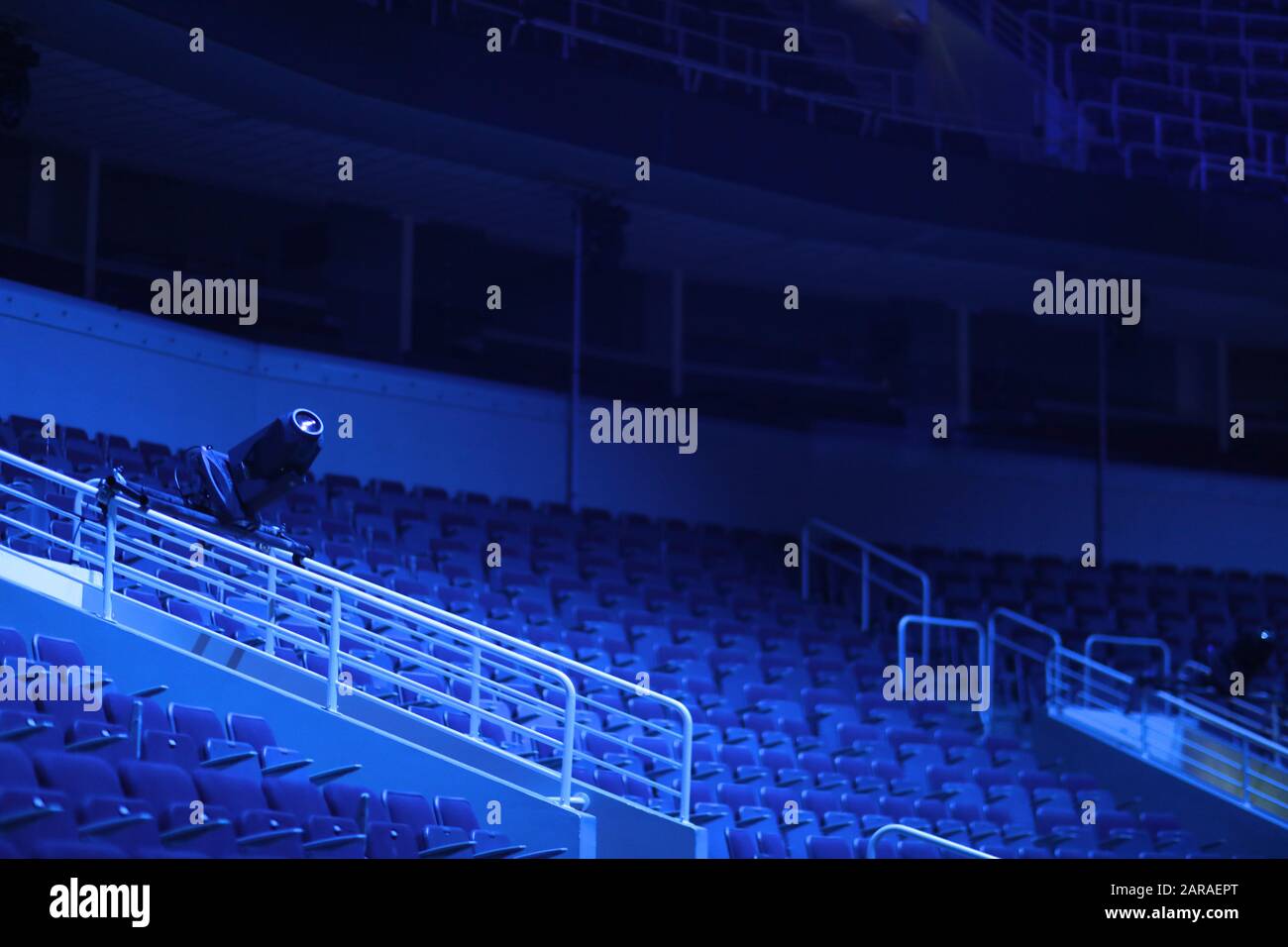 File vuote di sedili con braccioli in un auditorium multiuso alla luce dei fari blu Foto Stock