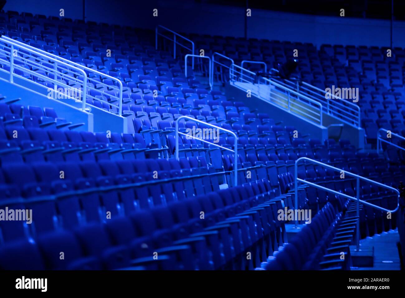 File vuote di sedili con braccioli in un auditorium multiuso alla luce dei fari blu Foto Stock File vuote di sedili con braccioli in un auditorium multiuso alla luce dei fari blu Foto Stock