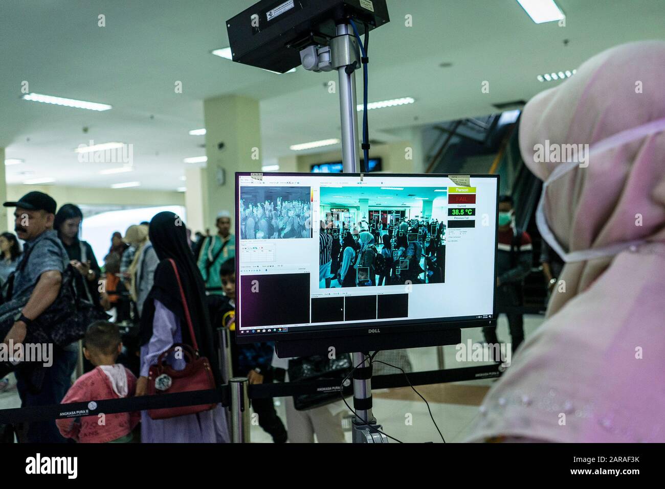 Un funzionario sanitario guarda i viaggiatori su un monitor termografico presso l'aeroporto internazionale Sultan Iskandar Muda di Aceh Besar Regency.il governo indonesiano ha annunciato che stava ufficialmente fermandosi voli per Wuhan Cina, un nuovo centro virus mortale, e controlli di salute negli aeroporti in Indonesia sono stati serrati. Foto Stock