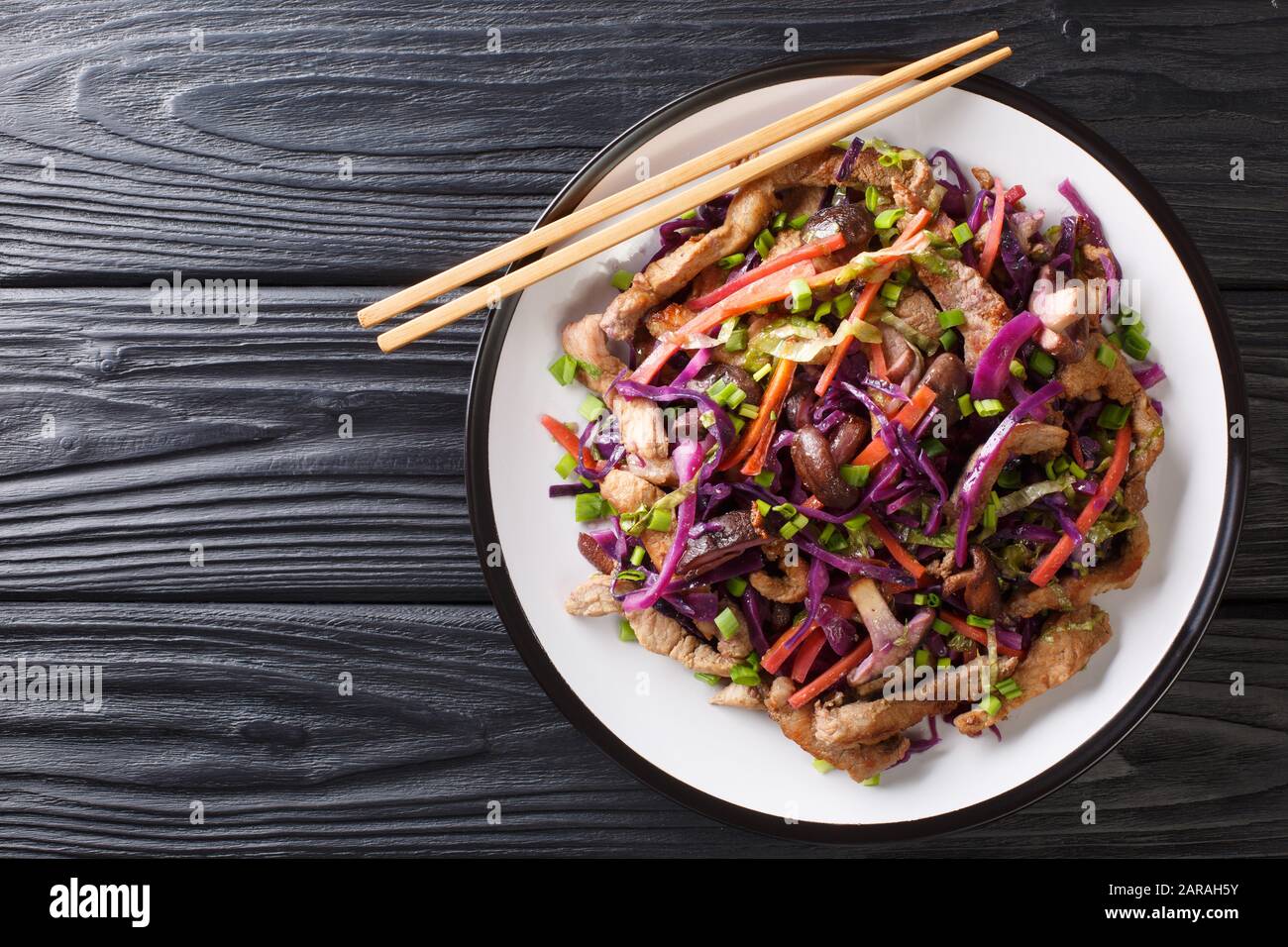 Cucina cinese maiale moo shu con verdure e funghi primo piano in un piatto sul tavolo. Vista dall'alto orizzontale Foto Stock