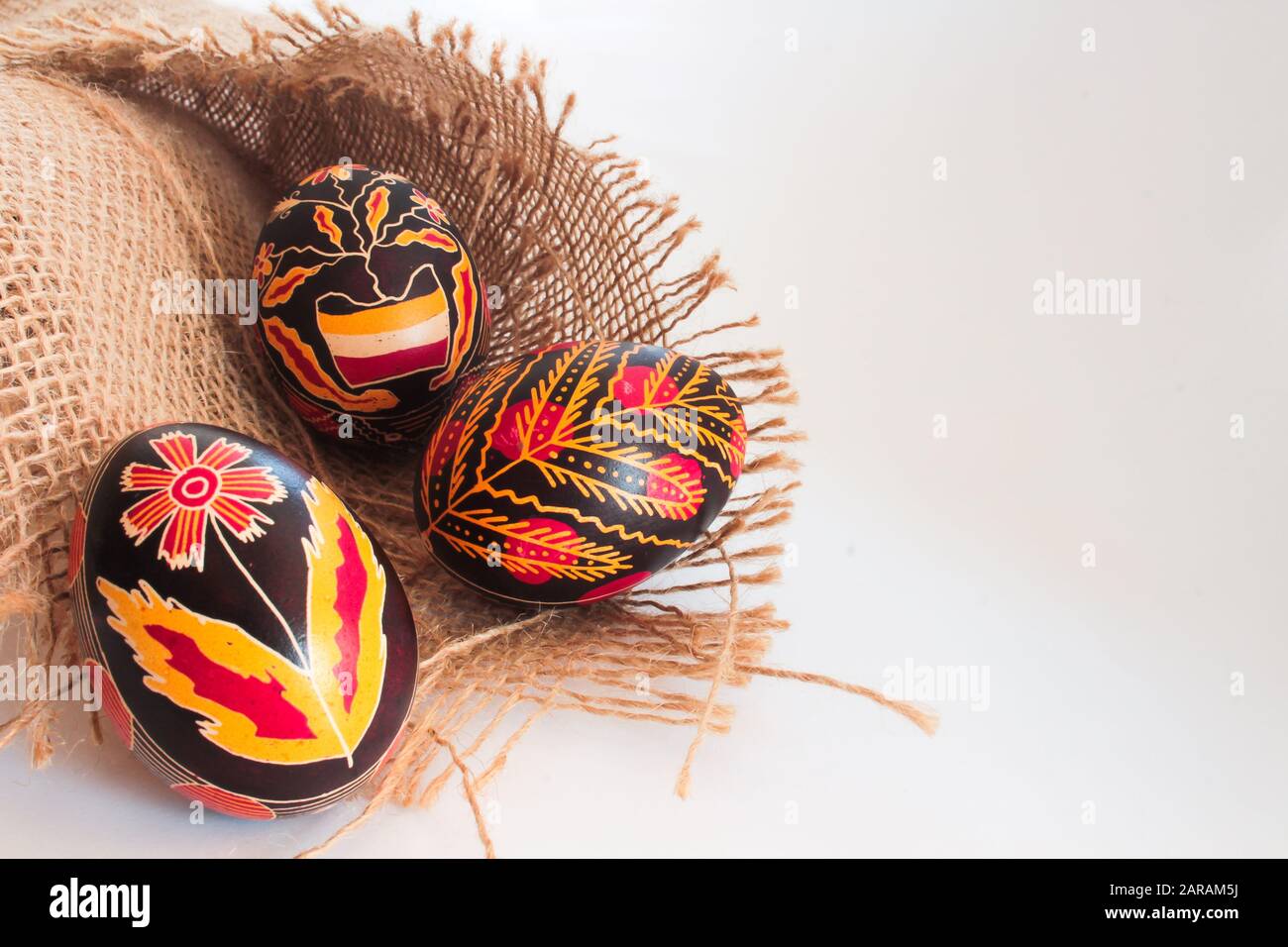 Tradizionale rumeno dipinto a mano uova di pasqua su materiale rustico marrone testurizzato isolato su bianco con copia spazio testo Foto Stock