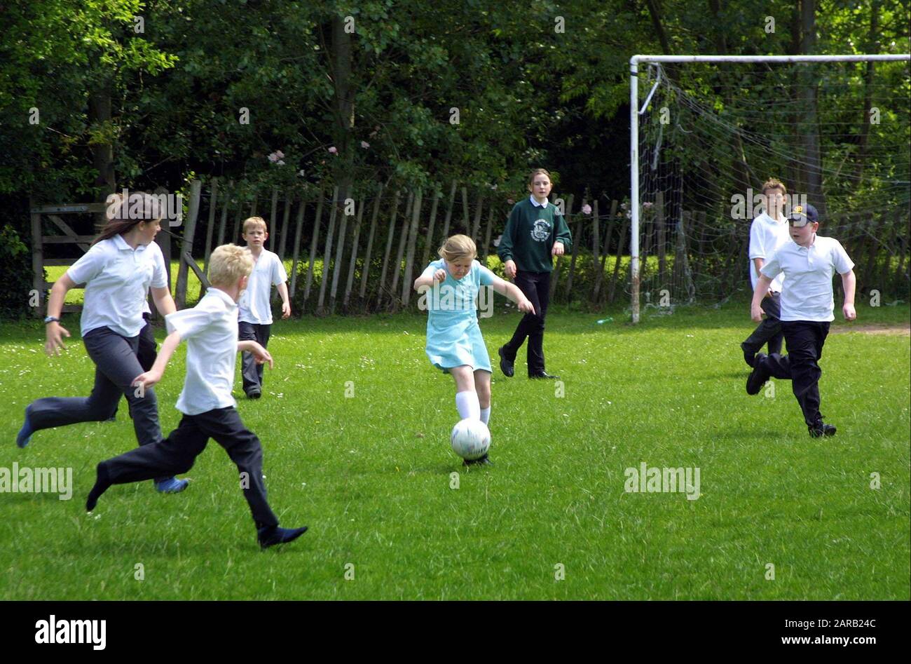 Gruppo misto di ragazzi e ragazze che giocano a calcio nel cortile della scuola Foto Stock