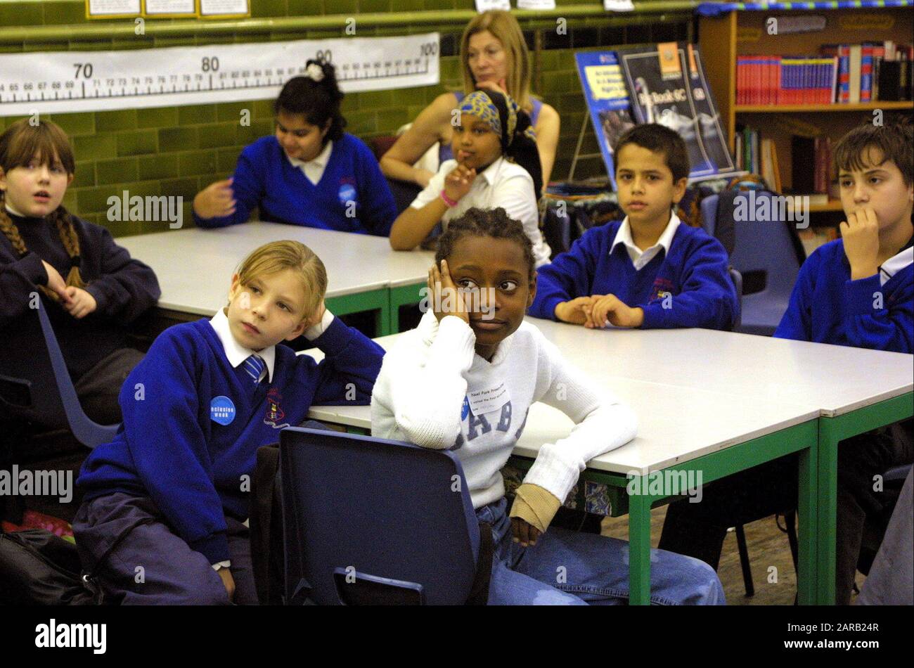 I bambini delle scuole elementari di varia etnia in uniforme ascolto di una lezione. Foto Stock