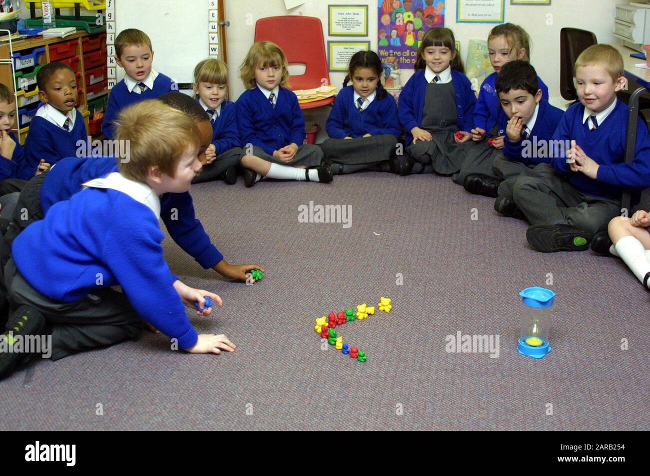 gli studenti primari uniorformed giocano con i blocchi sul pavimento dell'aula Foto Stock
