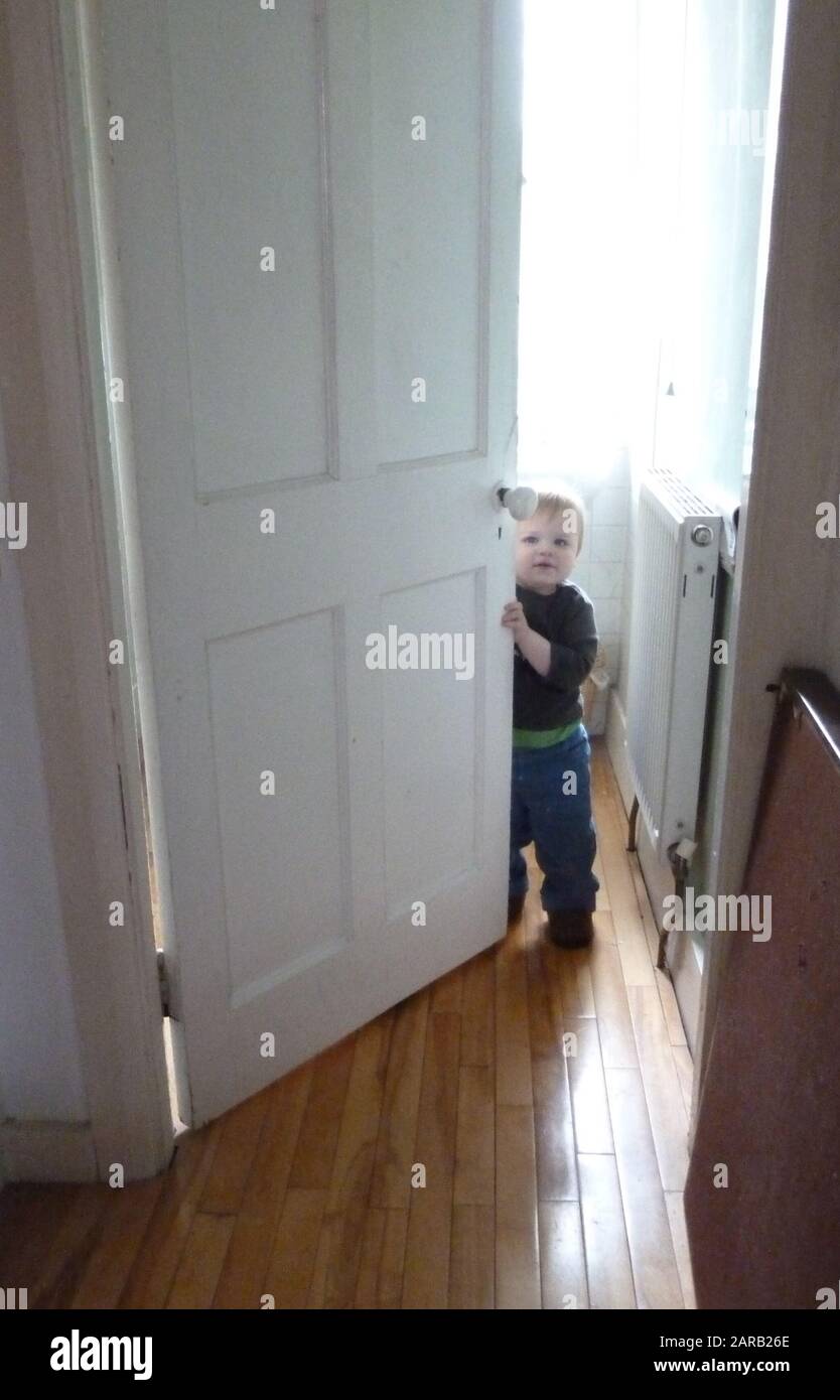 piccolo bambino che sta per chiudere una porta che guarda alla telecamera che potrebbe essere bloccata Foto Stock