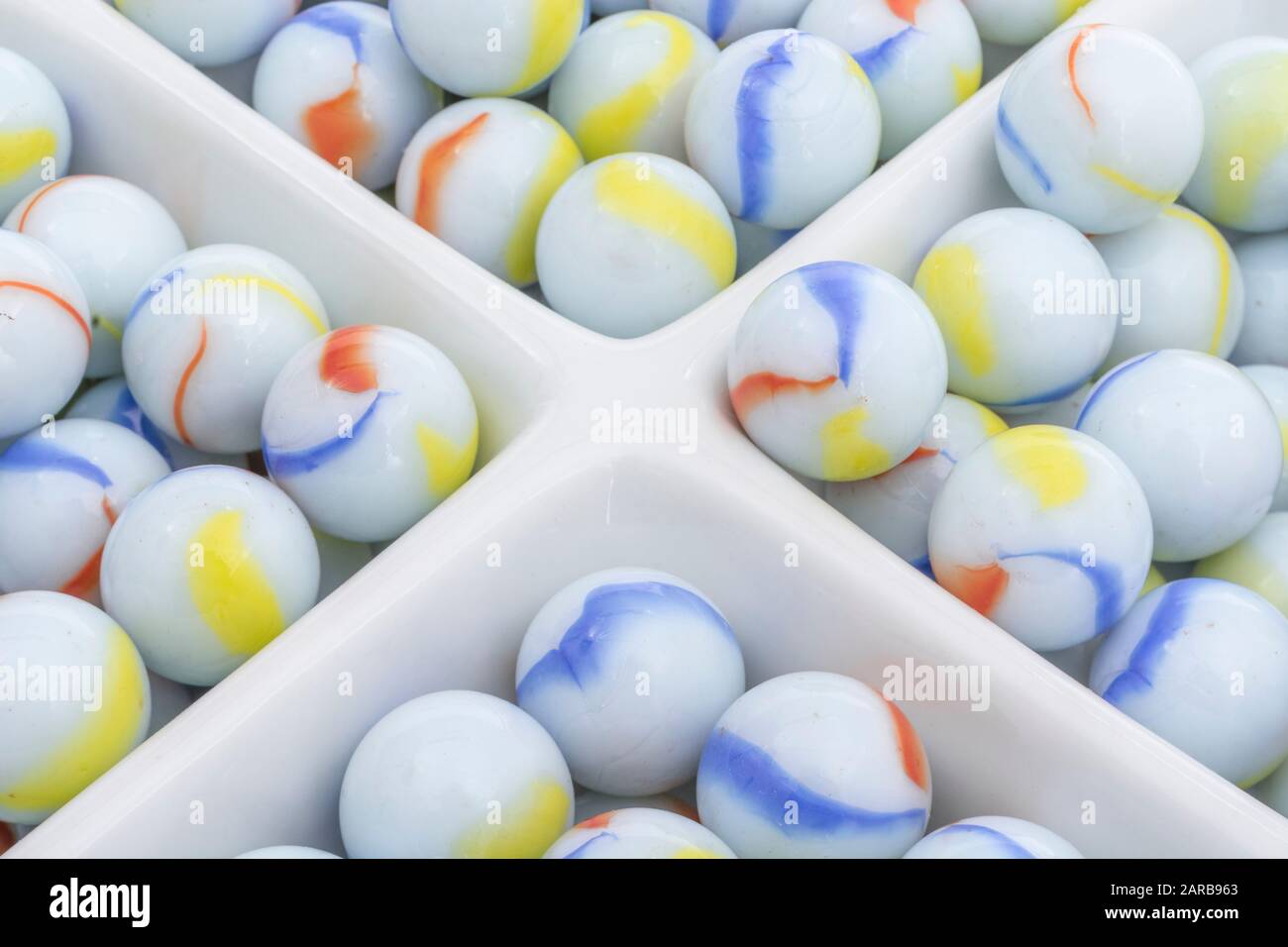 Marmi bianchi - non legati ai marmi Elgin in ceramica piatto - come metafora divisa. Divisi, sfere astratte, marmi giocattolo, perdere i marmi. Foto Stock