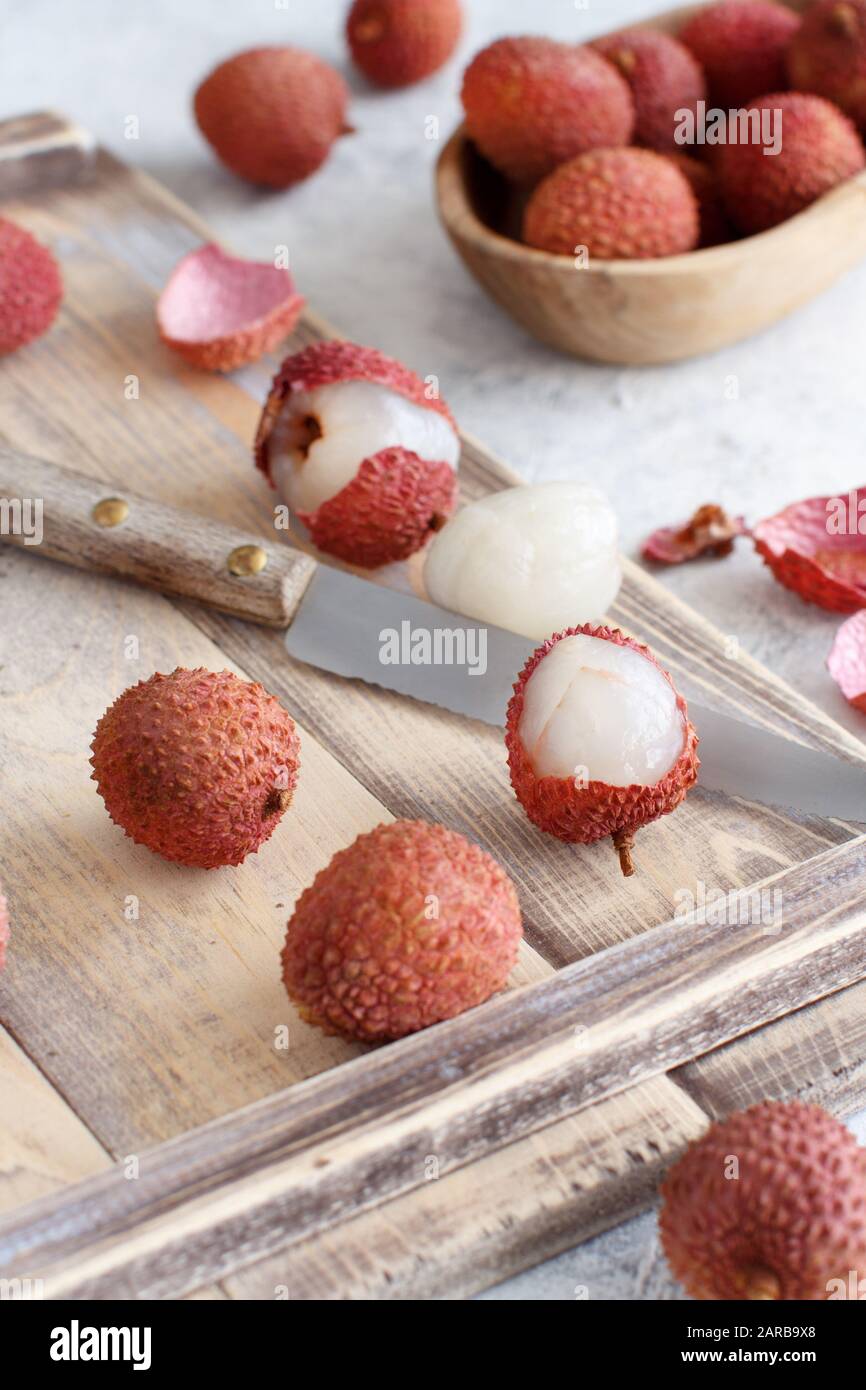 Litchi freschi frutti con un coltello su un tavolo bianco close up Foto Stock