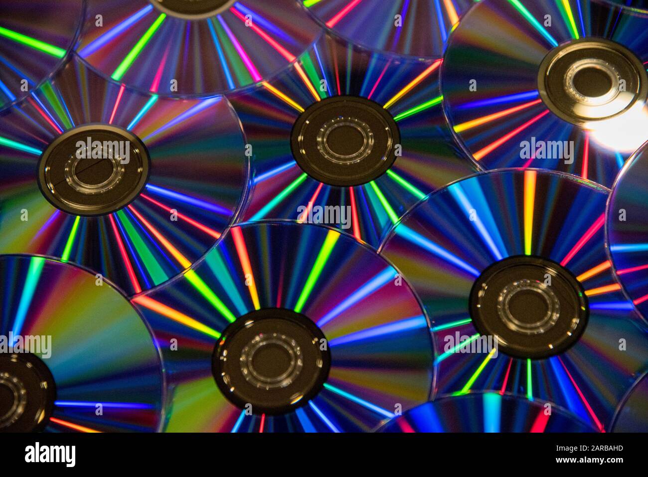 Molti compact disc musicali puliti con una gamma arcobaleno di colori come sfondo luminoso Foto Stock