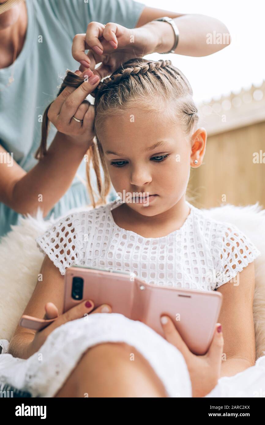 Madre fare la treccia di capelli a sua figlia, close up foto Foto Stock