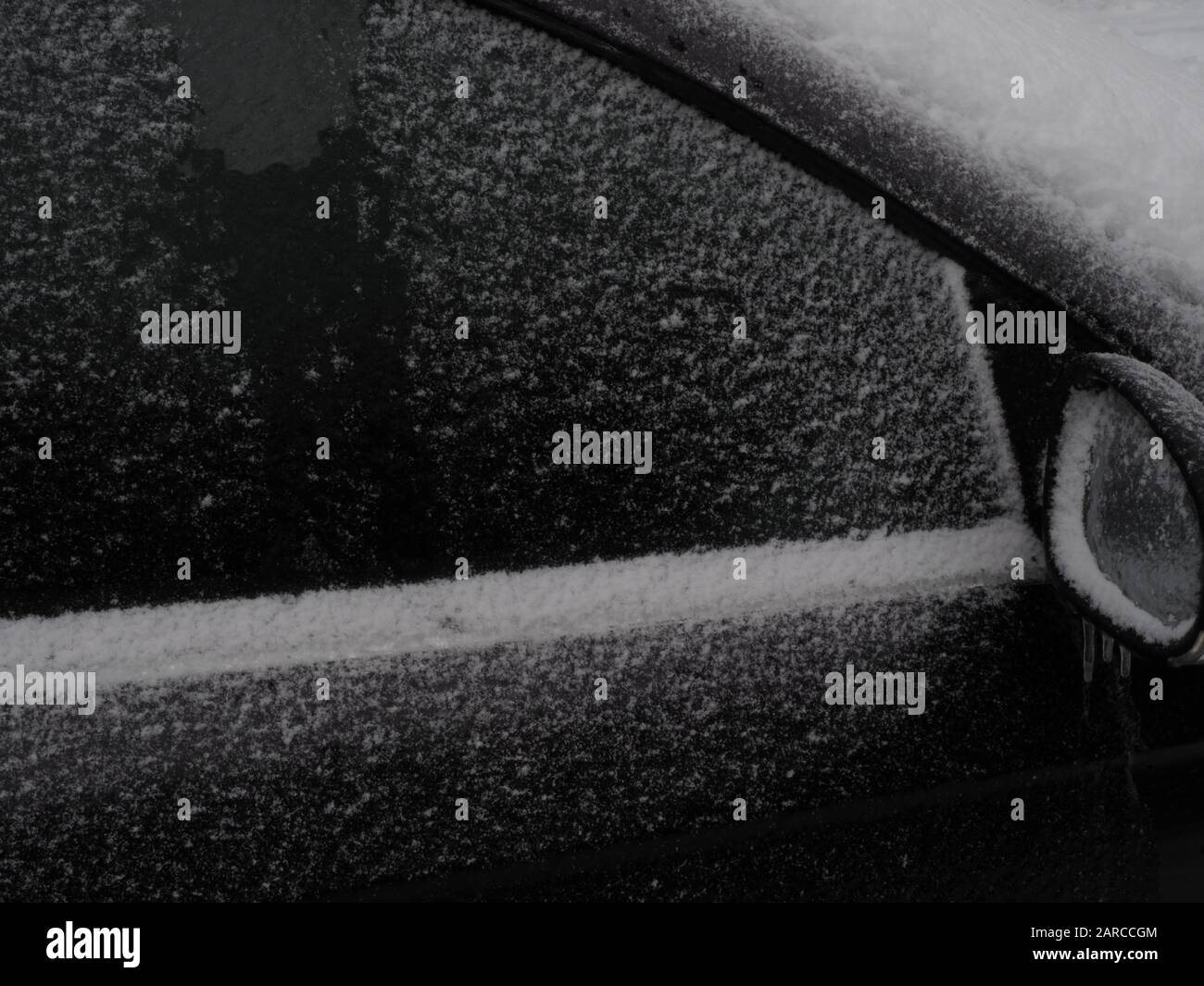 un finestrino e uno specchio per auto coperti da ghiaccio e neve Foto Stock