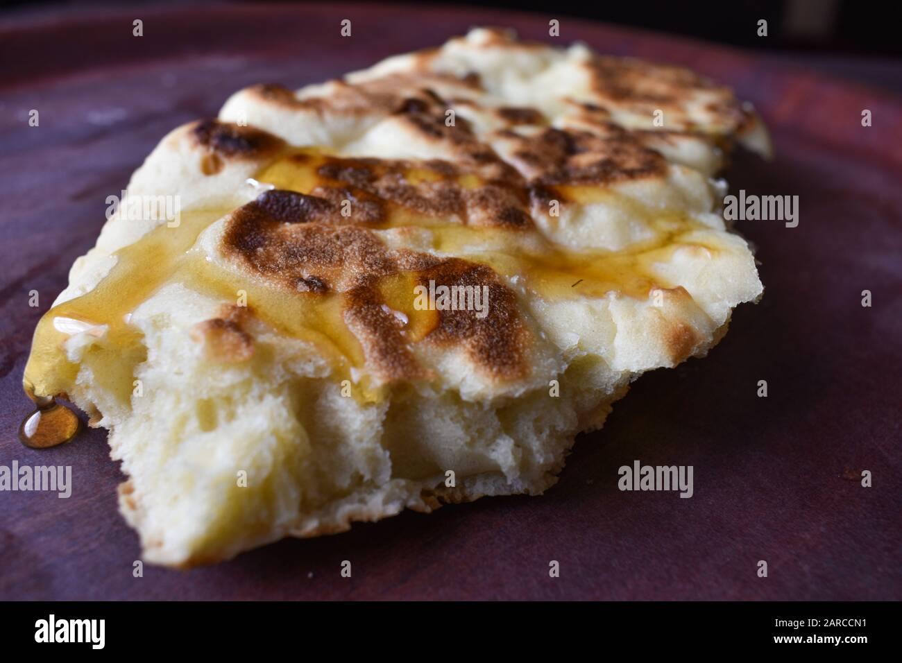 un pezzo di pane tradizionale etiope con miele che lo sgocciola sul vassoio di legno Foto Stock