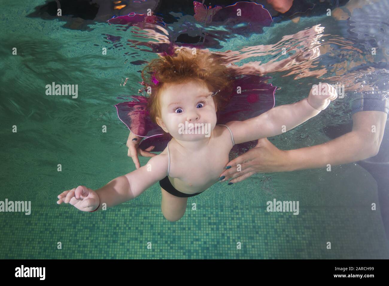 Ragazza piccola redhead in costume da elfo nuotare sott'acqua in piscina Foto Stock