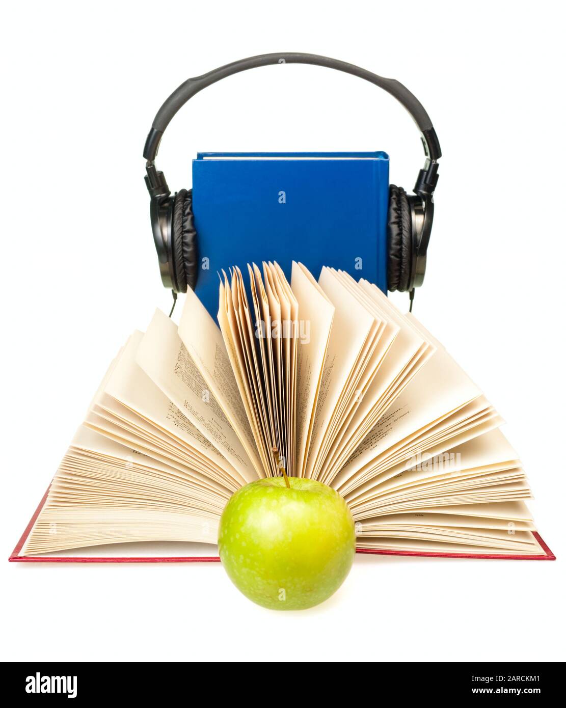 Libro aperto con mela verde e hi-fi cuffie sul libro blu a sfondo Foto Stock
