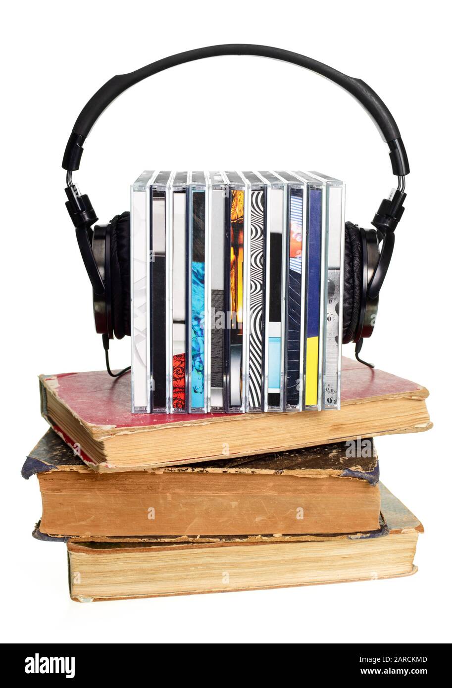 Pila di cd con hi-fi cuffie e vecchi libri su sfondo bianco Foto Stock