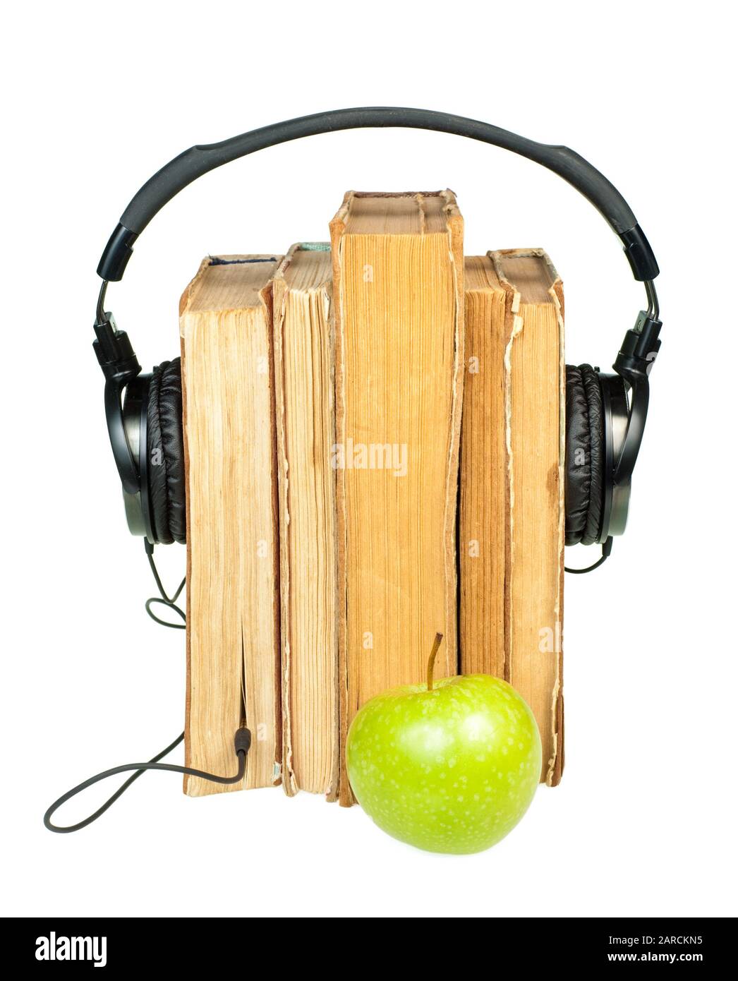 HI-Fi cuffie sulla pila di libri vecchi con mela verde su sfondo bianco Foto Stock