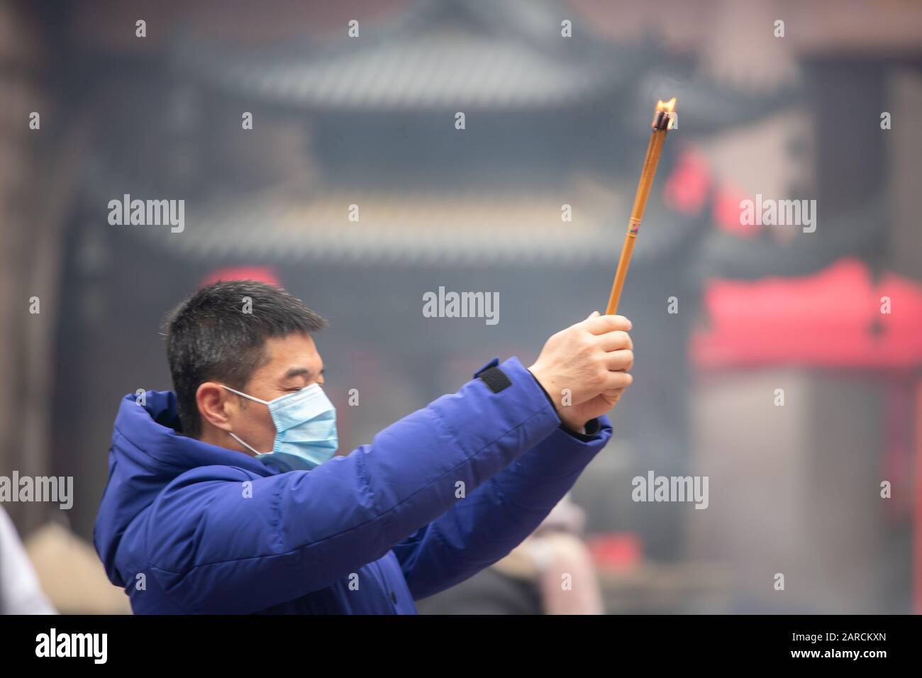 Shanghai, Cina, 23rd Jan 2020, un uomo che indossa una maschera prega con bastoncini di joss brucianti Foto Stock
