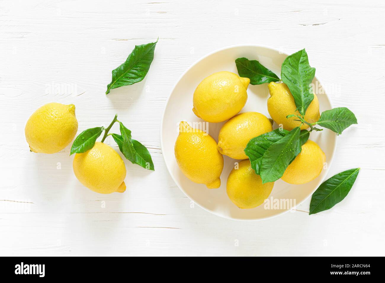 Limoni freschi con foglie su sfondo di legno bianco, ingrediente limonata estiva, concetto di vitamina c, vista dall'alto Foto Stock