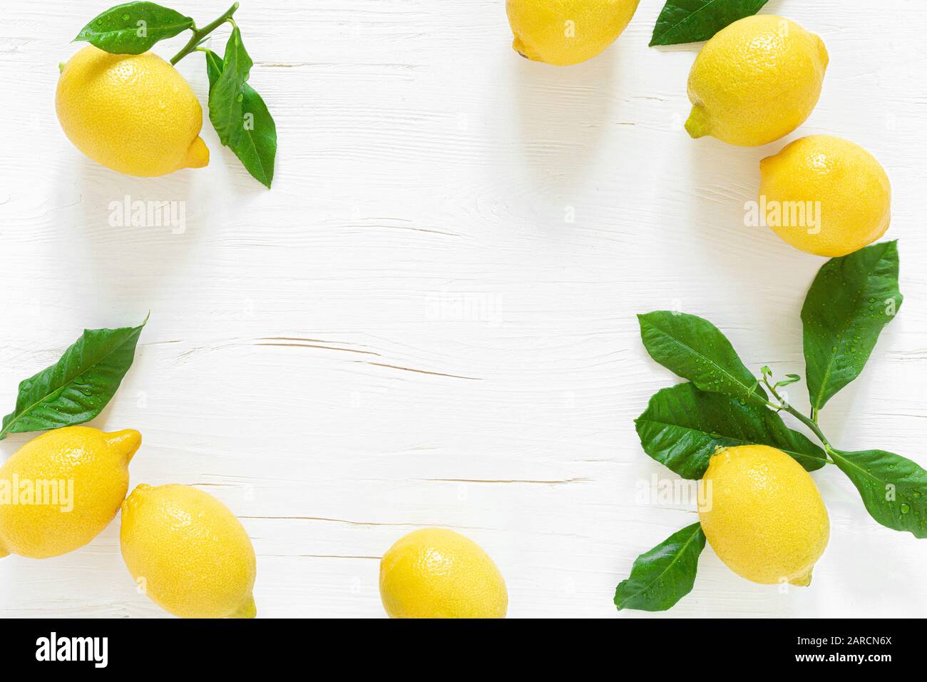 Limoni freschi con foglie su sfondo di legno bianco, ingrediente limonata estiva, concetto di vitamina c, vista dall'alto Foto Stock