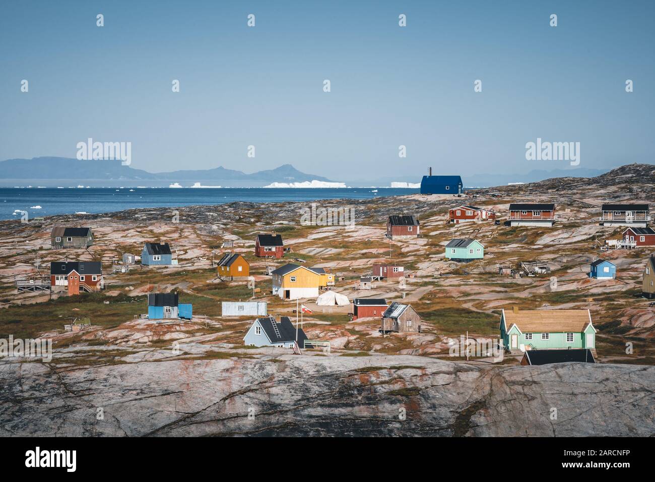 Tipica casa di pescatori in legno colorato blu con iceberg nella zona della baia di Disko Groenlandia e Ilulissat. Architettura tipica nel cerchio artico. Estate Foto Stock