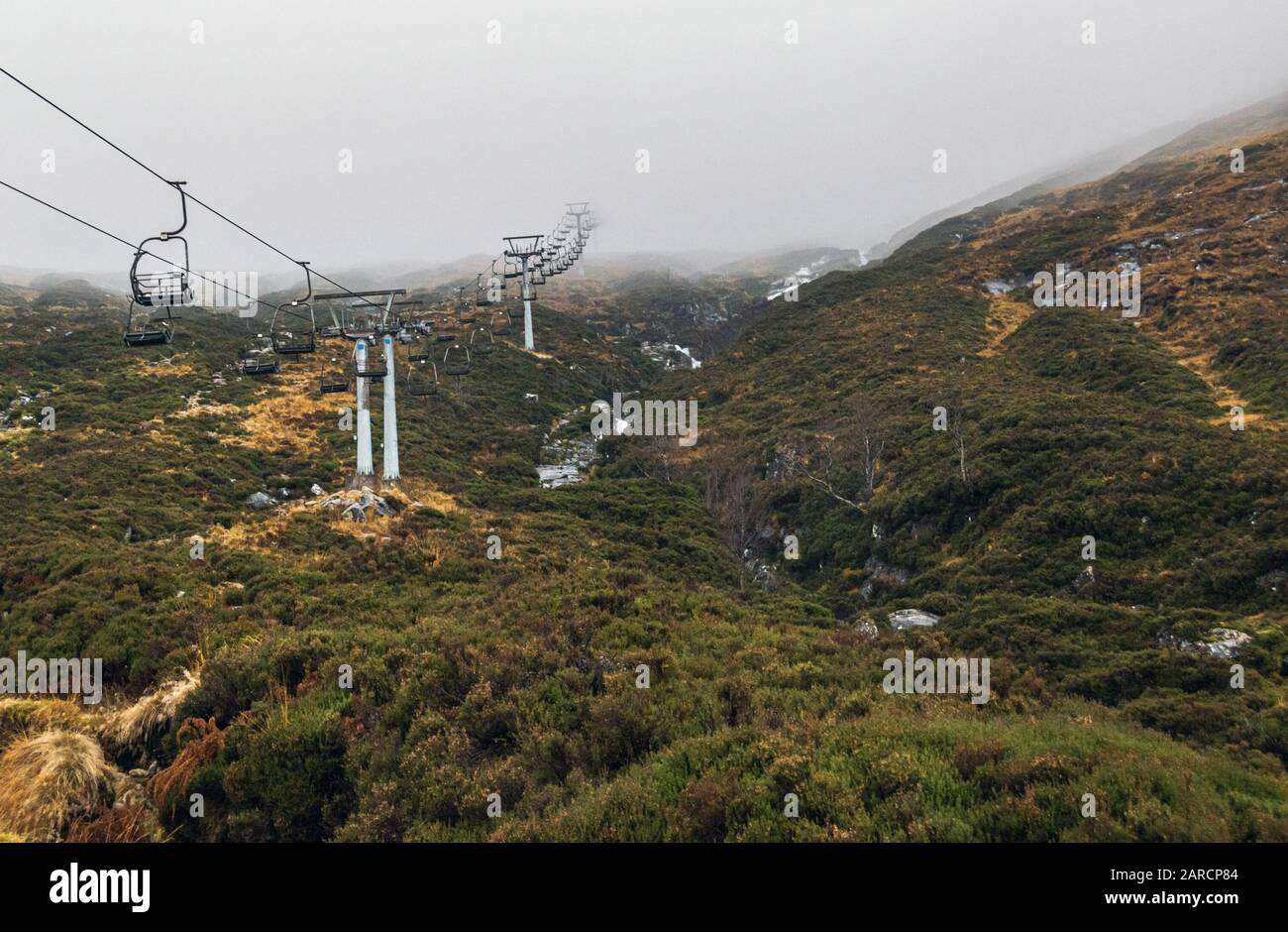 Skilift vuoto nel Glen Coe Ski Center, in Scozia, senza neve e le colline coperte di fitta nebbia. Foto Stock
