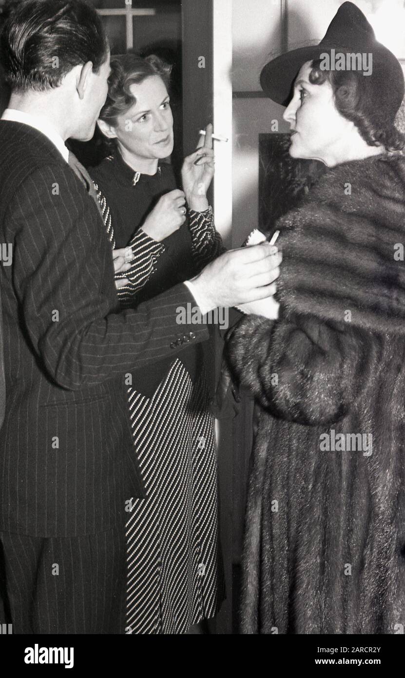1940s, ospiti storici, adulti in conversazione a una festa di bevande presso una galleria d'arte di Londra, Londra, Inghilterra, Regno Unito, indossando le mode del giorno, con una signora in un cappotto e cappello di pelliccia di lusso. Foto Stock