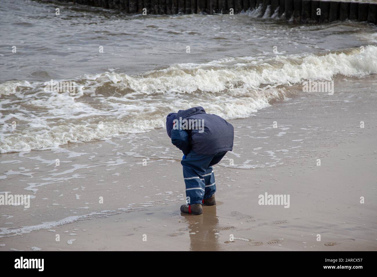 Un ragazzino corre sulla spiaggia di Zempin sull'isola di Usedom e gioca con le onde Foto Stock