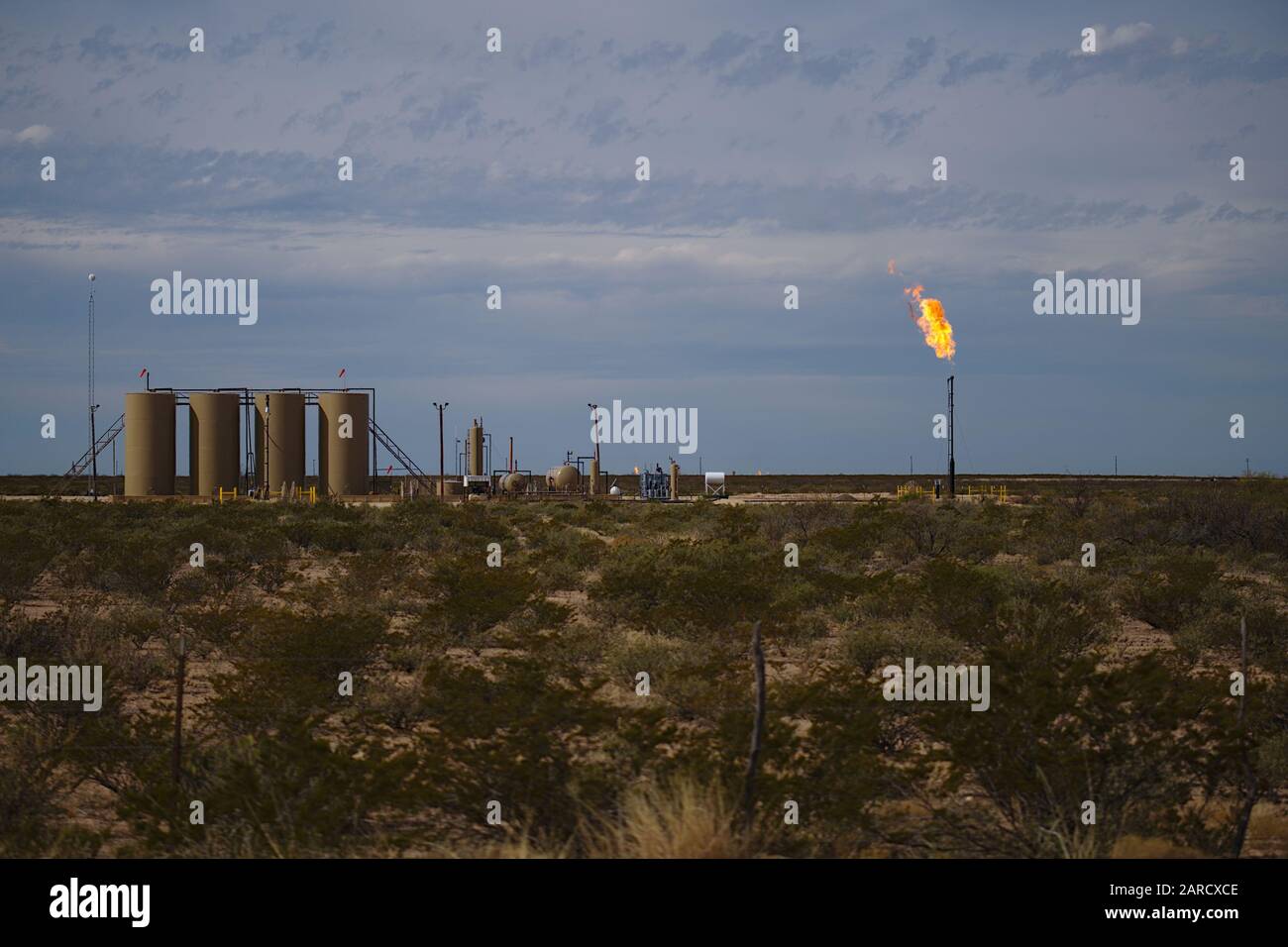 Permian Basin gas Flare - bruciare il gas naturale in eccesso in un sito di stoccaggio del petrolio greggio è una pratica comune quando i prezzi del gas lo considerano antieconomico. Foto Stock