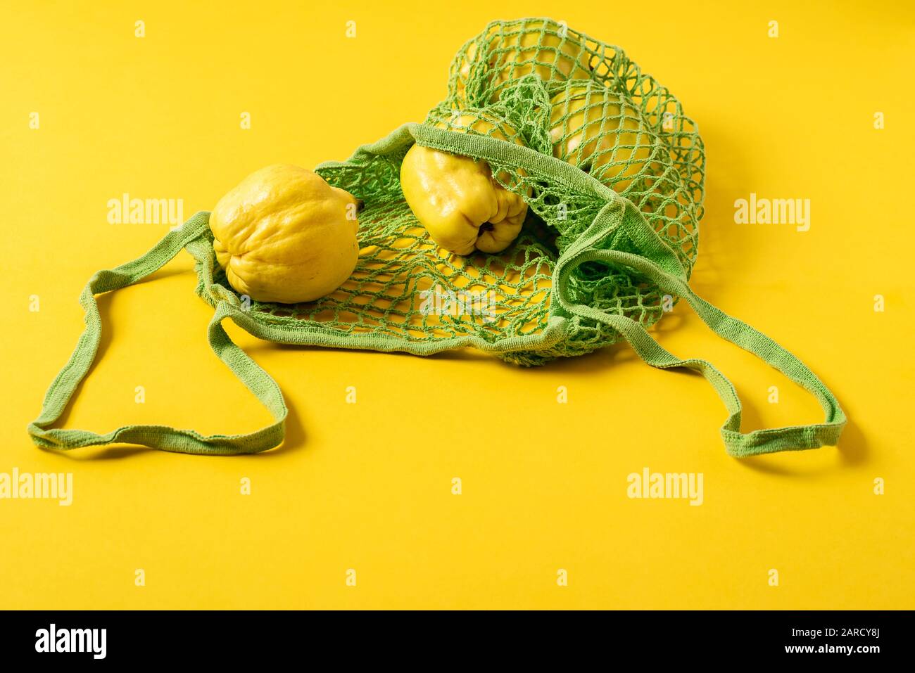 Frutta fresca di mele cotogne in un sacchetto di tessuto netto su fondo giallo. Borsa per lo shopping ecologica e frutta. Sacchetto riutilizzabile per alimentari. Ridurre l'inquinamento della plastica. Foto Stock